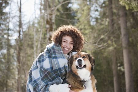woman with curly hair hugging a dog
